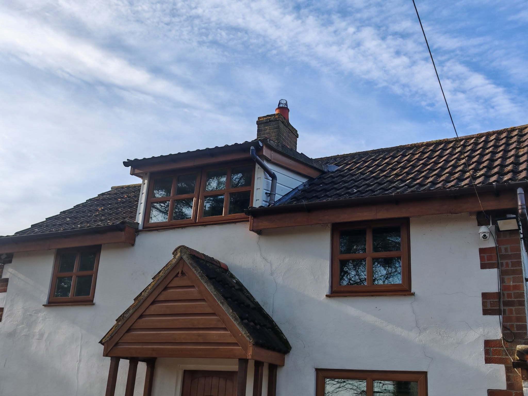 A white house with a dormer and porch under a clear blue sky, windows freshly cleaned